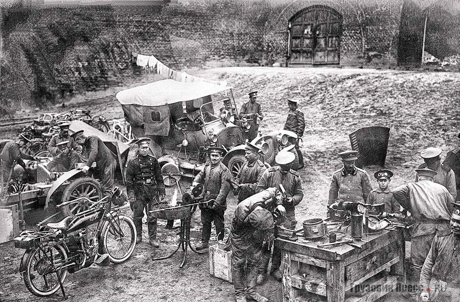 Ремонт автомобилей в походных условиях. Техника из довоенных поставок: на переднем плане американский мотоцикл Indian, на заднем штабной автомобиль «Русско-Балтийский», среди солдат чины 2-й и 3-й автомобильных рот. Действующая армия, 1915 г.