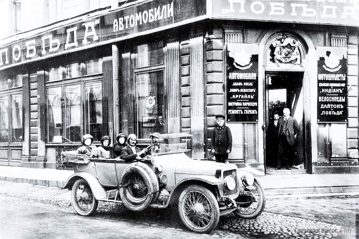 Торговые залы на Мойке 61 (доходный дом М.Ф. Раудзе постройки 1857 г., архитектор Р.А. Желязевич при участии А. Робена и Н.П. Гребёнки, 1857 г.). Адрес дома: Мойка, 61 / Кирпичный, 8 / Большая Морская, 16. В дверях стоит Ф.И. Танский, за рулём автомобиля Argyll его партнёр Н.В. Соколов, 1911 г.