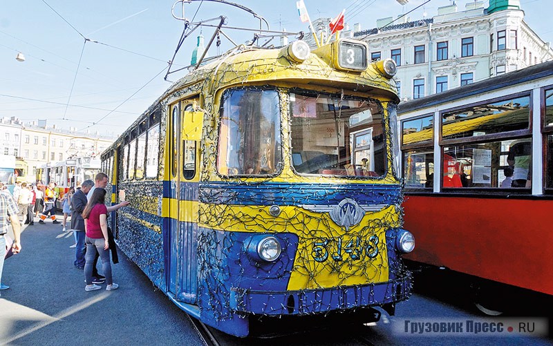 [b]ЛМ-57 (1968 г.).[/b] «Стиляга» ЛМ-57, опутанный паутиной гирлянд к празднику – один из красивейших трамваев не только Ленинграда, но и СССР. ЛМ-57 выпускался заводом ВАРЗ-1 с 1957 по 1969 год. Впервые в Ленинграде сиденья трамвая были выполнены мягкими, а в тележках использовались подрезиненные колёса, которые сделали вагон менее  шумным и более скоростным