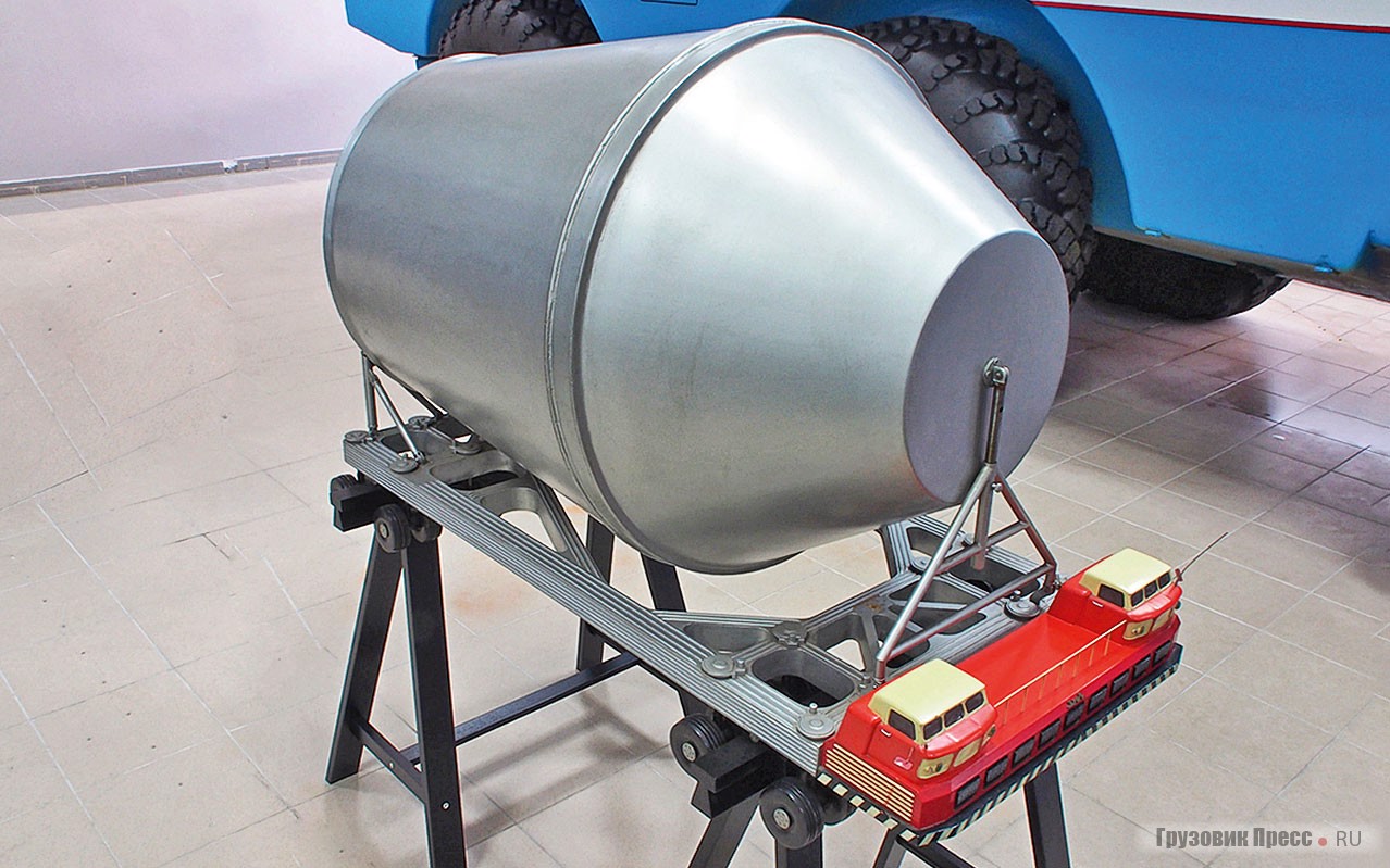 Макет [b]транспортёра ЗИЛ-135Ш грузоподъёмностью 120 т[/b] для перевозки модулей ракеты Н-1 для полёта на Луну. Транспортёр опирается на 16 стоек, аналогичных стойкам шасси самолёта Ил-18. Поскольку Ил-18 был первым нашим самолётом с АБС (в авиации систему называли «антиюзовым автоматом растормаживания»), транспортёру предстояло стать первым отечественным автомобилем с дисковыми тормозами и антиблокировочной системой. После смерти С.П. Королёва 14 января 1966 года новый «космический» генеральный конструктор В.П. Мишин изменил концепцию, решил строить сборочный завод прямо на космодроме, и необходимость в гигантском (колея – 11,2 м, рама – 10,8х21,1 м) транспортёре отпала