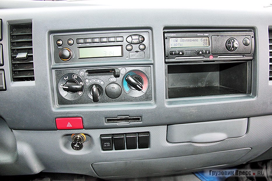Справа от водителя – блок управления отопителем, 24-вольтовый прикуриватель, два выдвижных подстаканника, штатный тахограф и головное устройство простенькой аудиосистемы